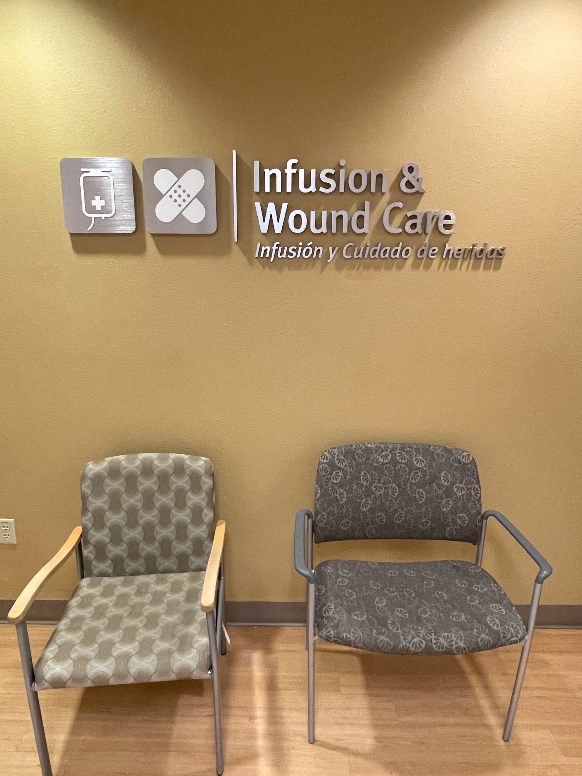 Two patterned chairs sit against a beige wall with Infusion & Wound Care signage.
