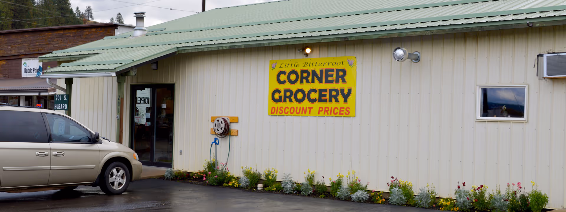 Exterior view of a beige storefront with a bright yellow Corner Grocery sign.