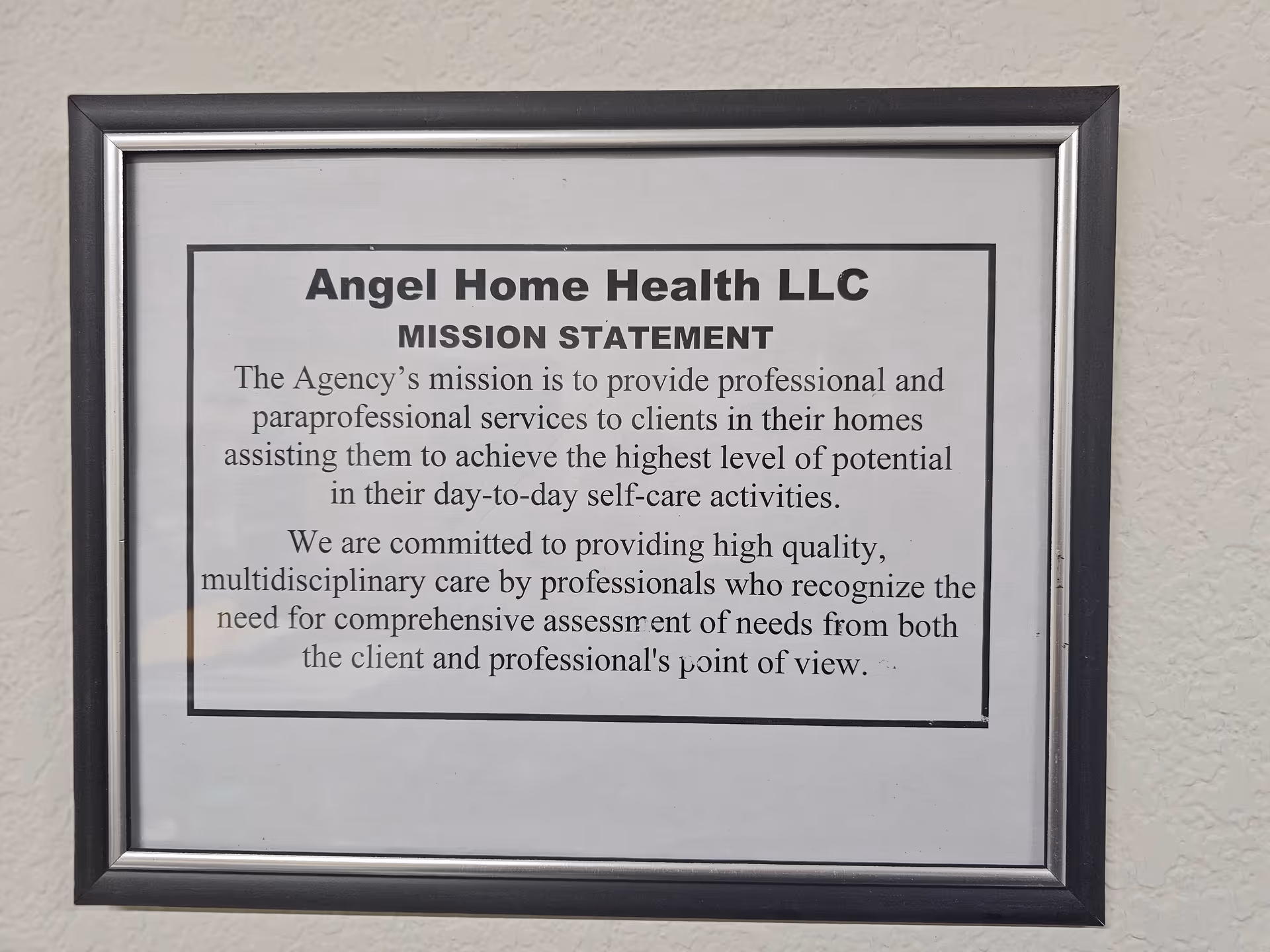 Framed mission statement for Angel Home Health LLC on a beige wall.