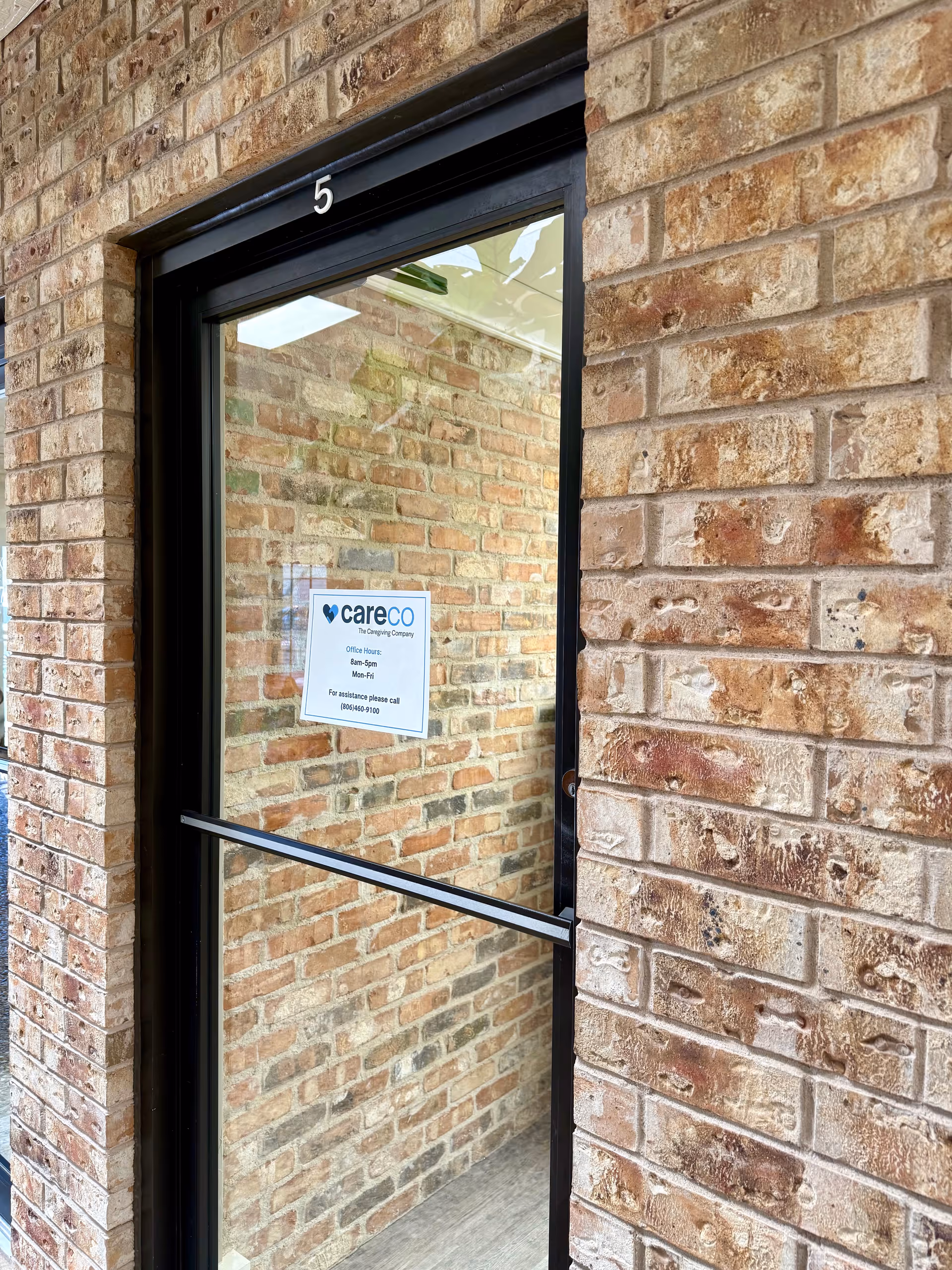 Brick exterior entrance with glass door and a careCO sign.
