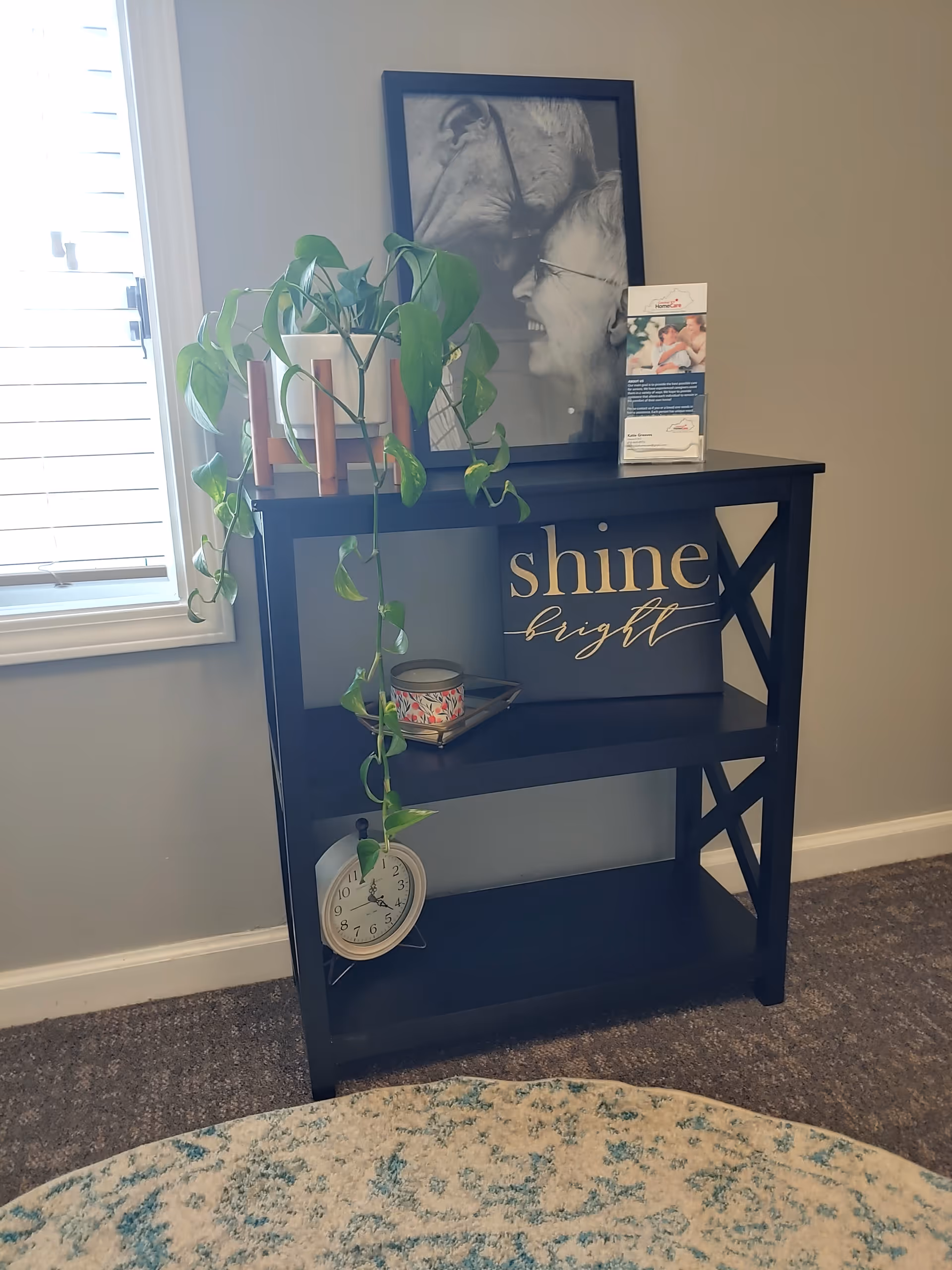 Blue shelf with plant, framed photo, and shine bright decor near a window