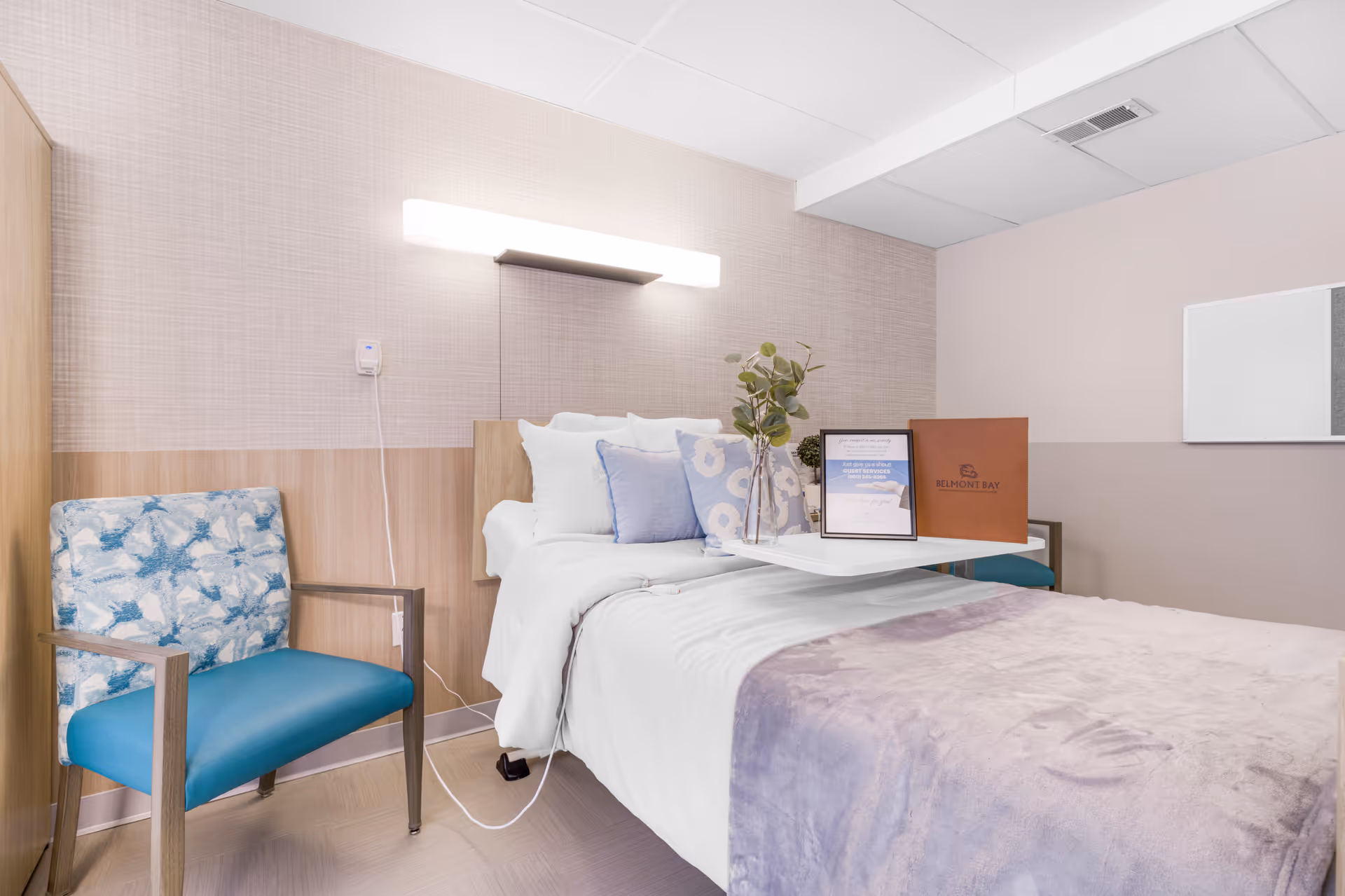 Pastel-toned senior living bedroom with a bed, chair, and bedside decor.