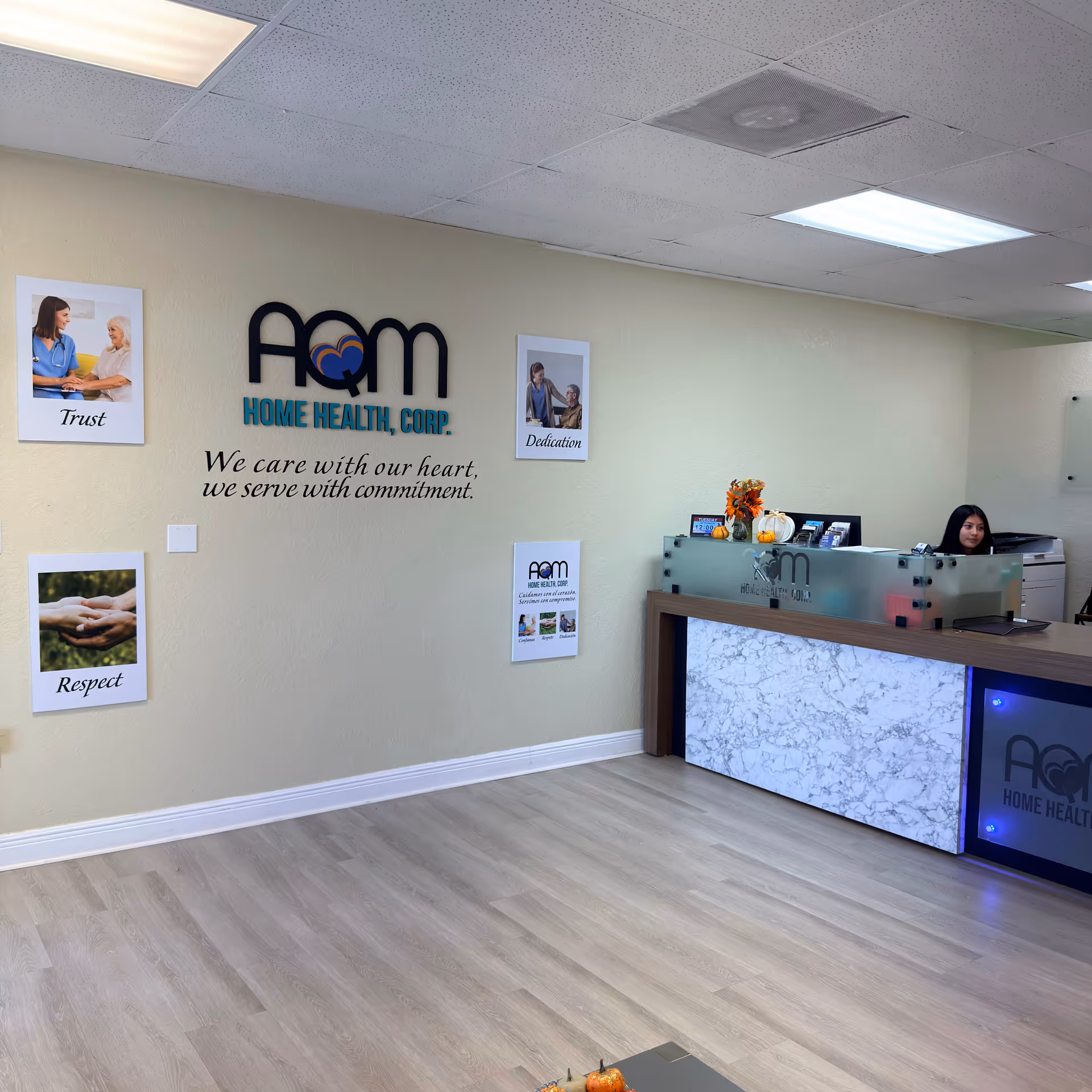 Reception area displaying AQM Home Health Corp logo, decor, and a receptionist at the desk.