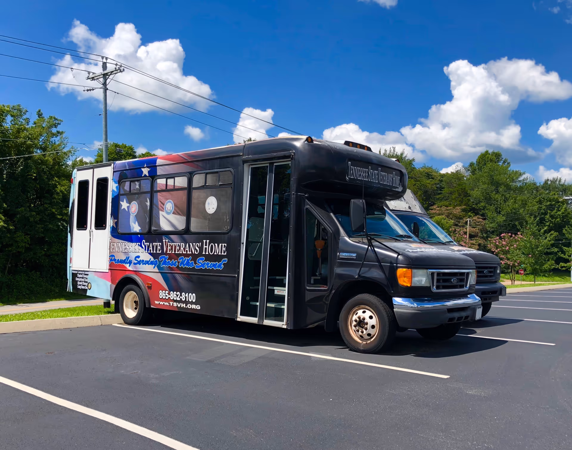 A black outreach bus for Tennessee State Veterans' Home parked in a lot.