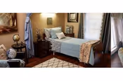 Cozy bedroom in a senior living facility with a neatly made bed and furnishings.