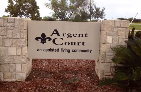 Stone entrance sign reads Argent Court, an assisted living community, with surrounding landscaping.