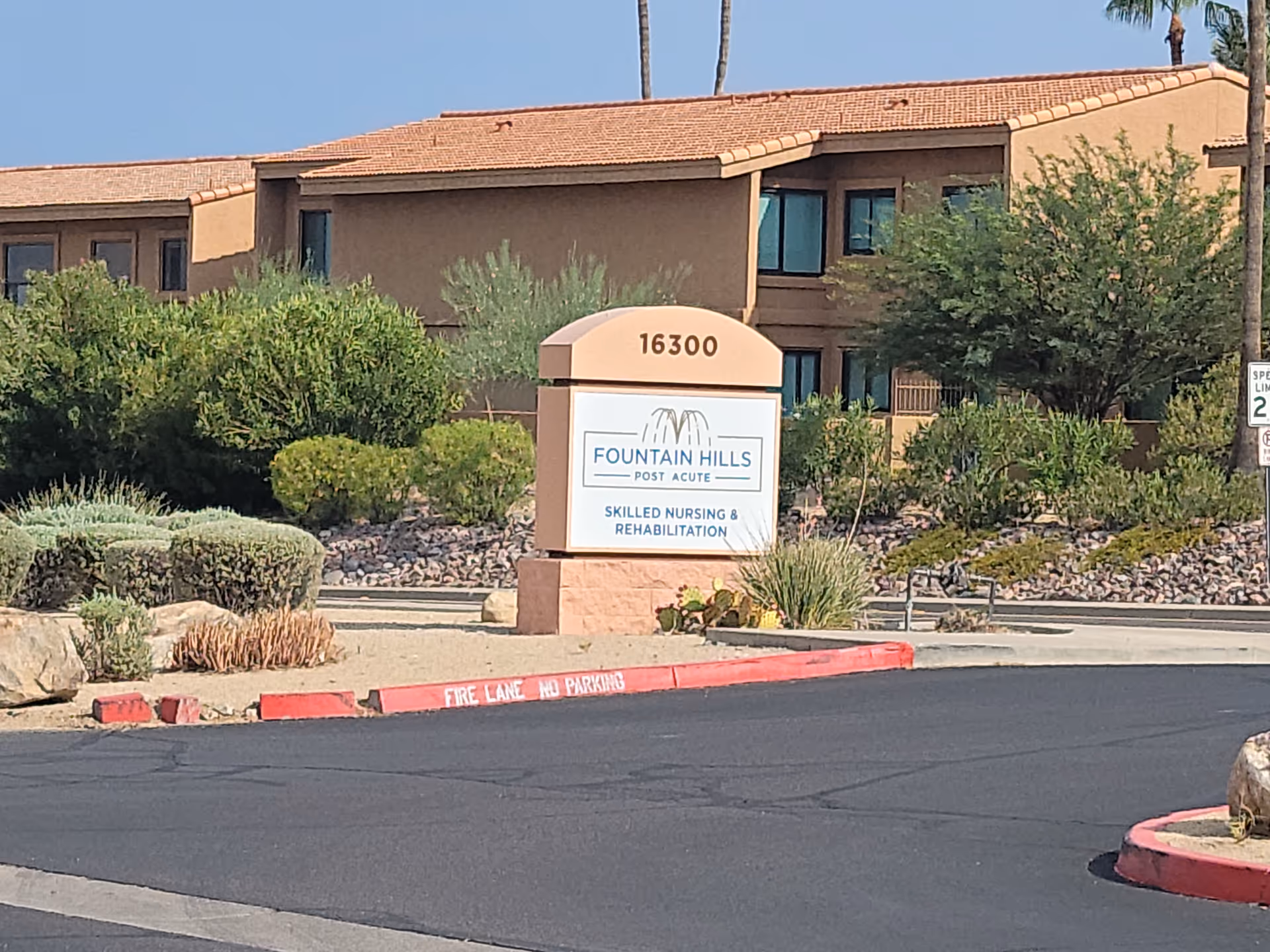 Exterior view of Fountain Hills Post Acute sign beside the building and desert landscaping.