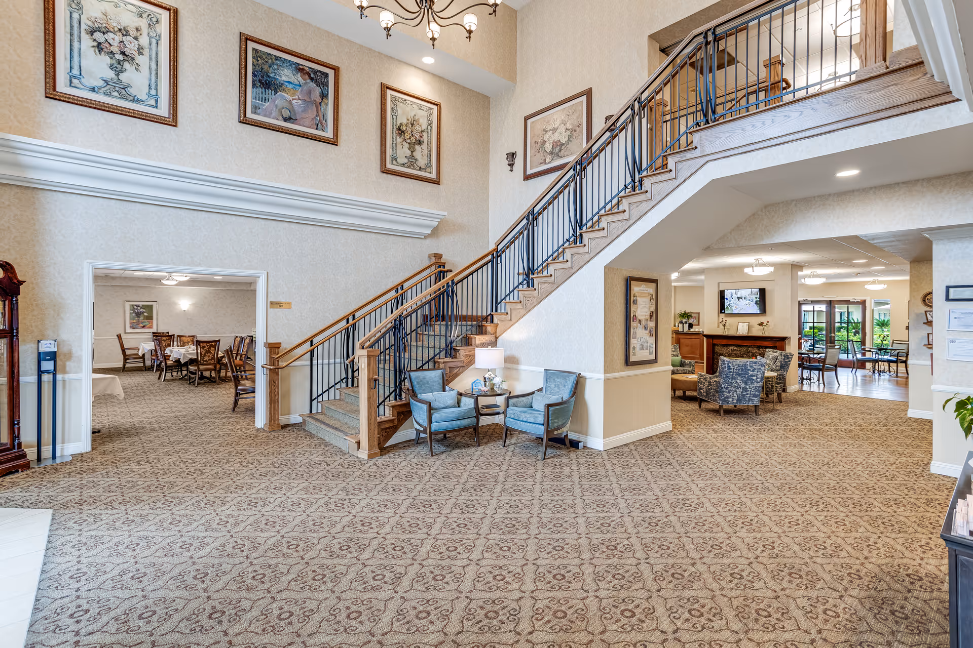 Sunrise of Yorba Linda lobby with staircase, chandeliers, patterned carpet, and resident seating.