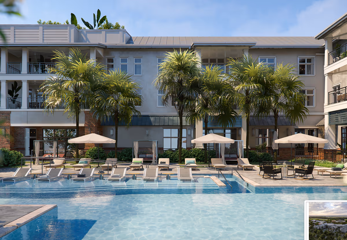 Outdoor swimming pool area at Seafields at Kiawah Island with lounge chairs, umbrellas, palm trees, and a multi-story building in the background under a clear blue sky.