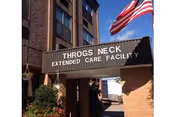 Exterior view of Throgs Neck Rehabilitation and Nursing Center entrance with an American flag.