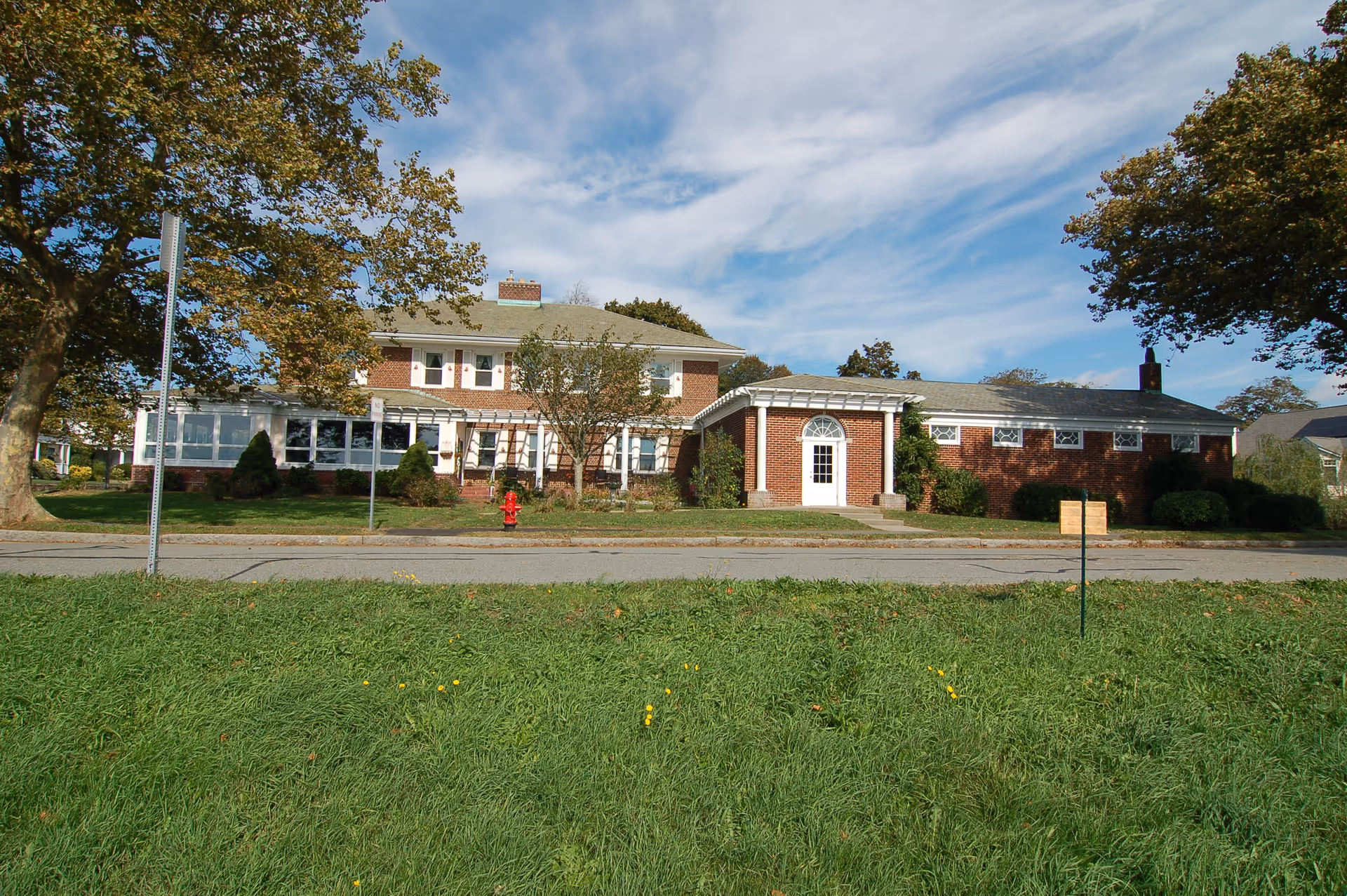 Exterior view of a brick senior care facility with a front entrance and manicured lawn.
