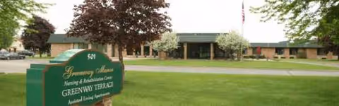 Exterior view of Greenway Manor facility with sign and manicured lawn.