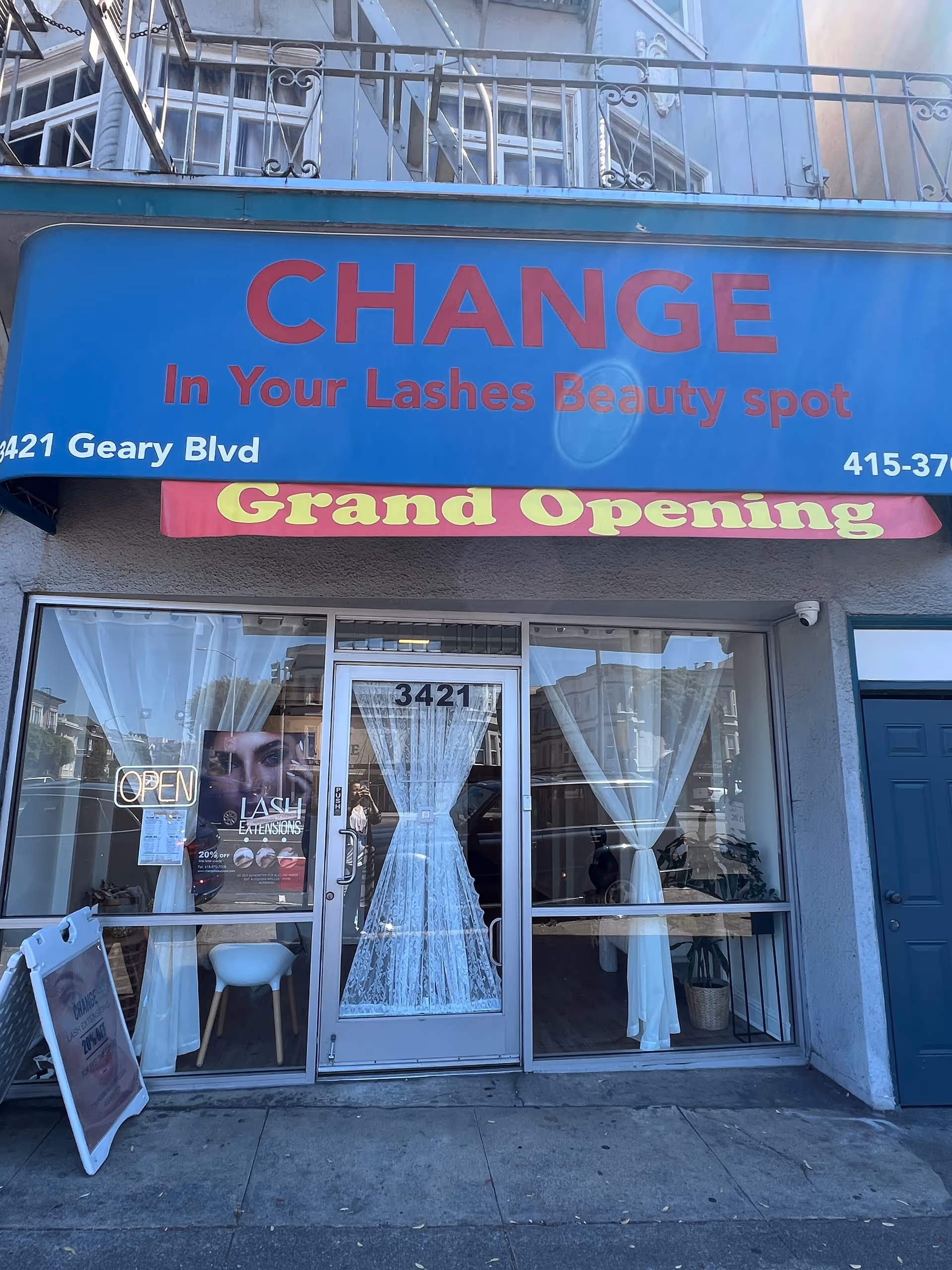 Blue storefront with grand opening banner and Change In Your Lashes Beauty spot sign