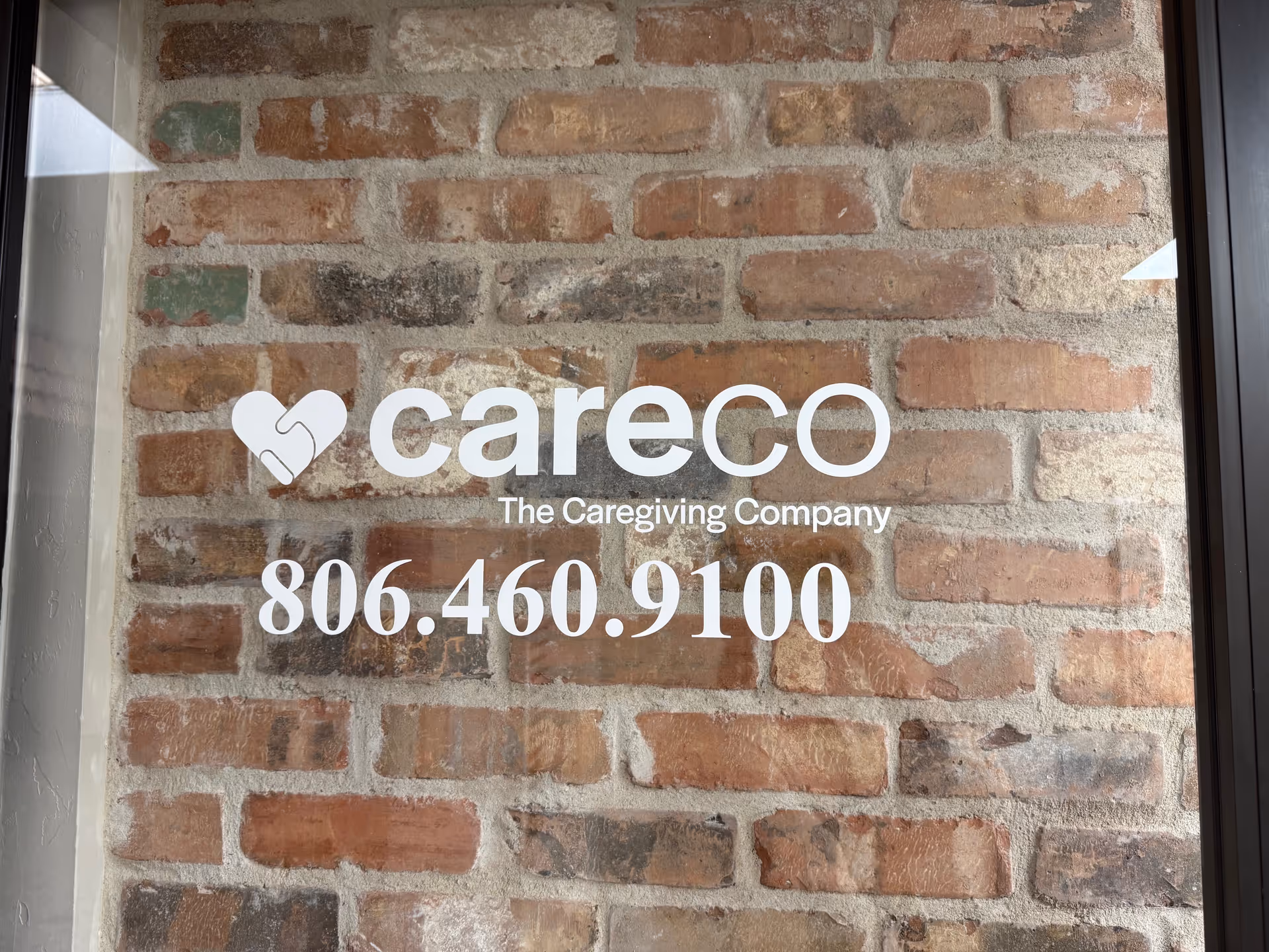 Brick exterior wall featuring CareCo logo, The Caregiving Company text, and phone number 806.460.9100.