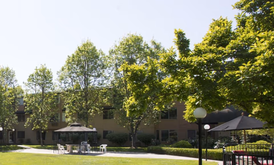 Exterior view of Bethel Retirement Community with outdoor seating under umbrellas.