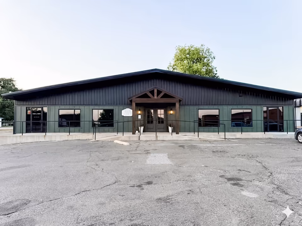 Front exterior of a single-story green and black building with a central entrance.
