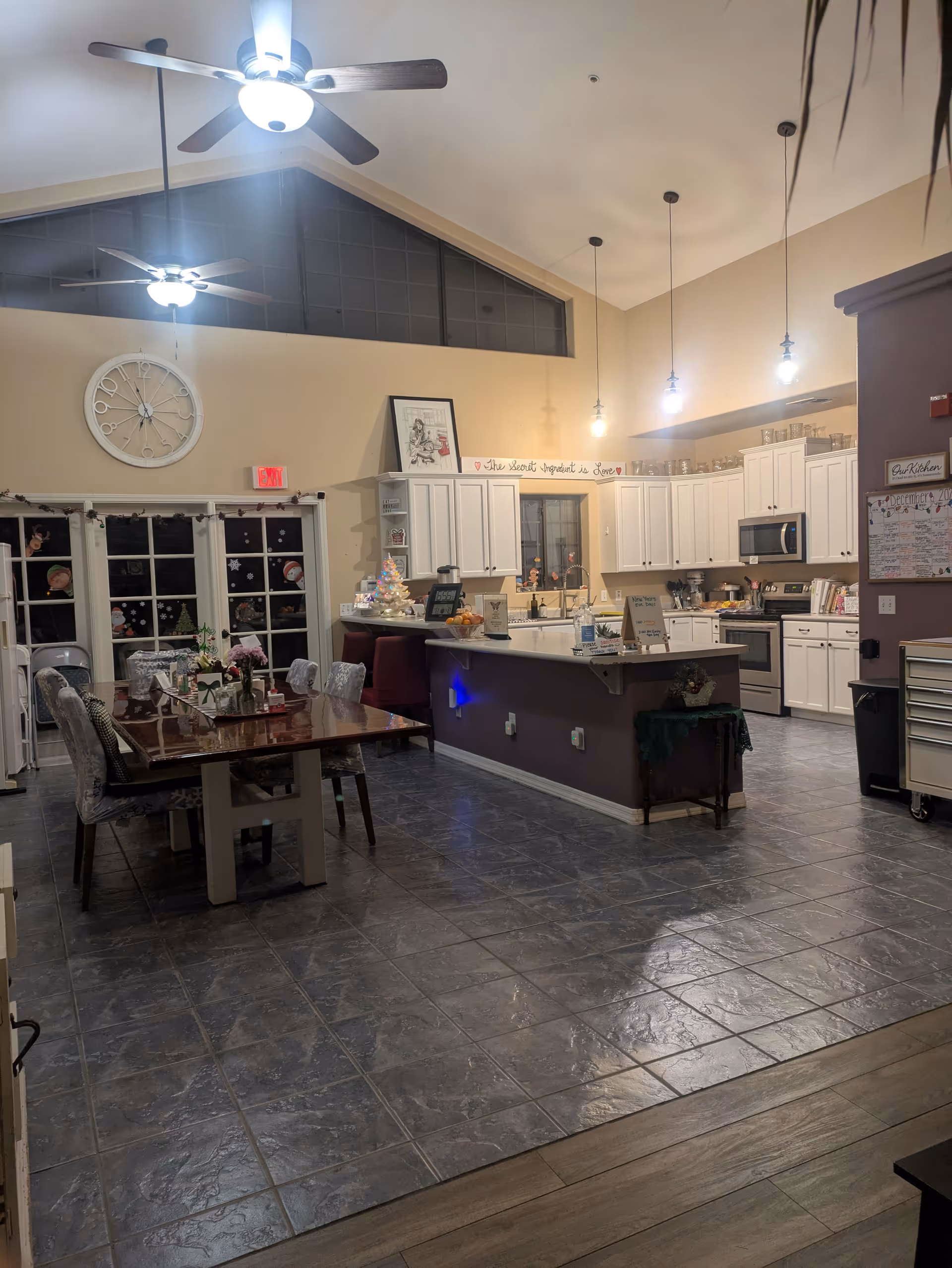Open concept dining and kitchen area with white cabinetry, island, dining table, and ceiling fans.