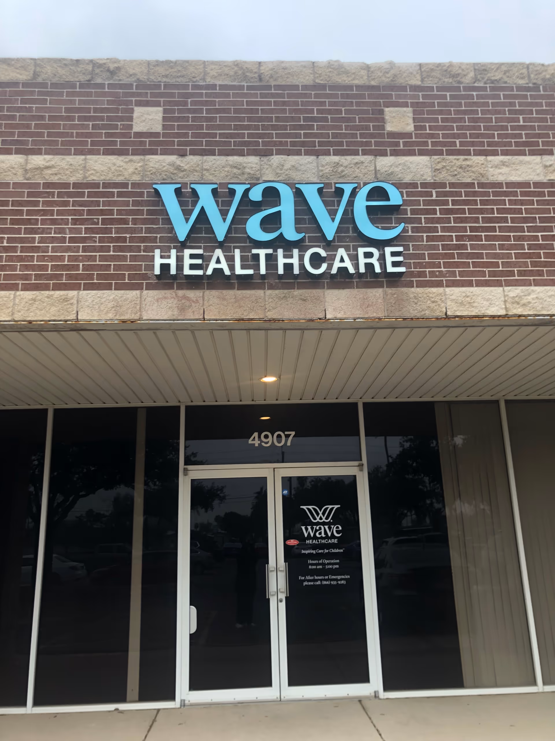 Exterior view of Wave Healthcare entrance with blue 'wave' sign on brick façade.
