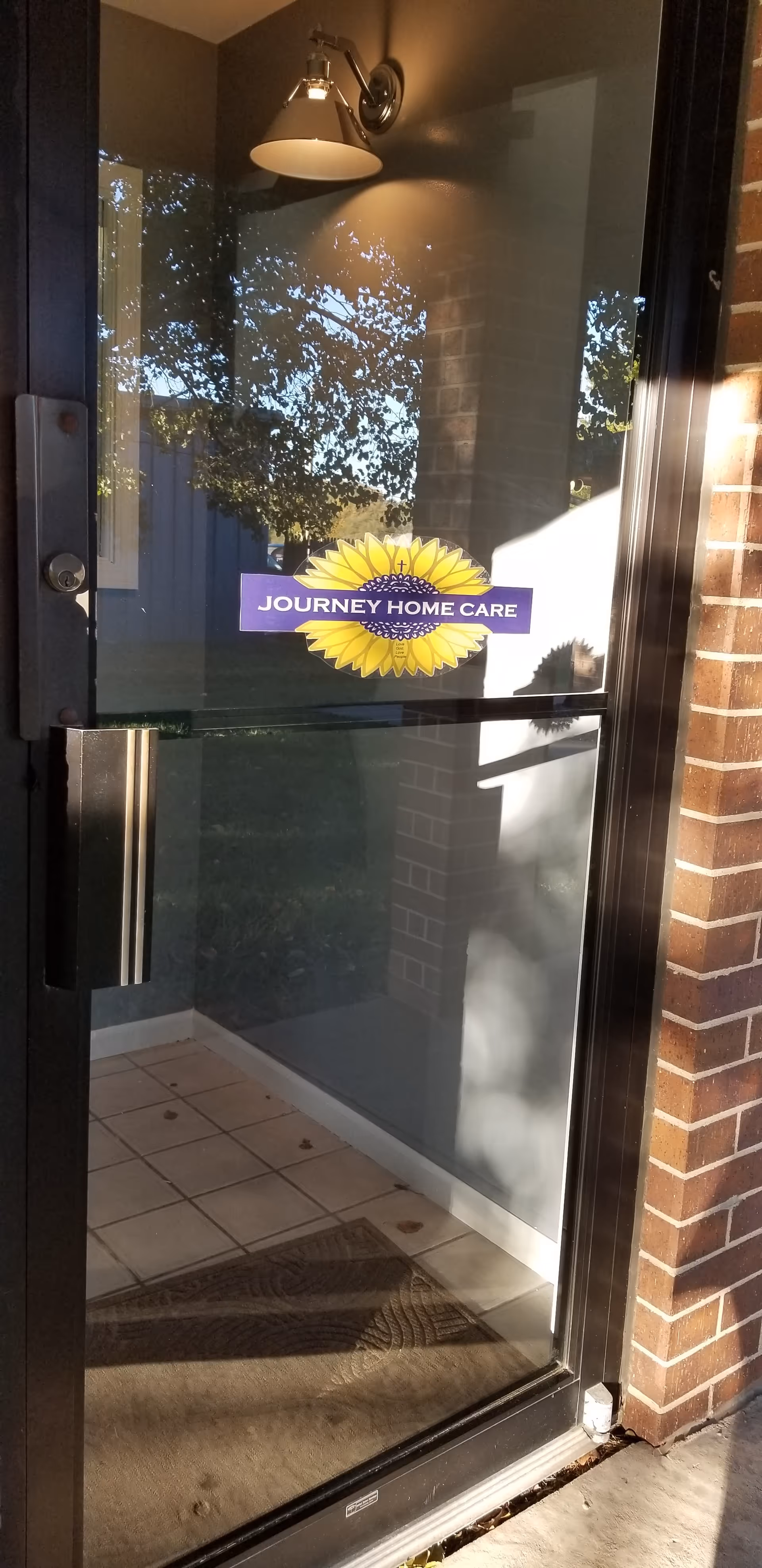 Glass entrance door of Journey Home Care with sunflower logo on front.