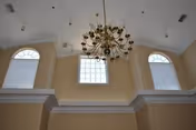 Beige interior with a high ceiling, chandelier, and arched windows.
