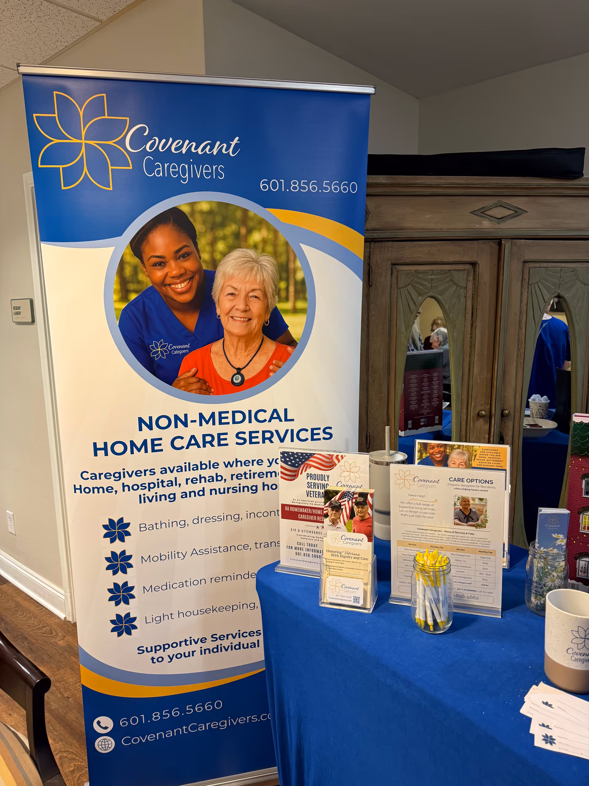 Indoor promotional banner for Covenant Caregivers home care beside a blue tablecloth.