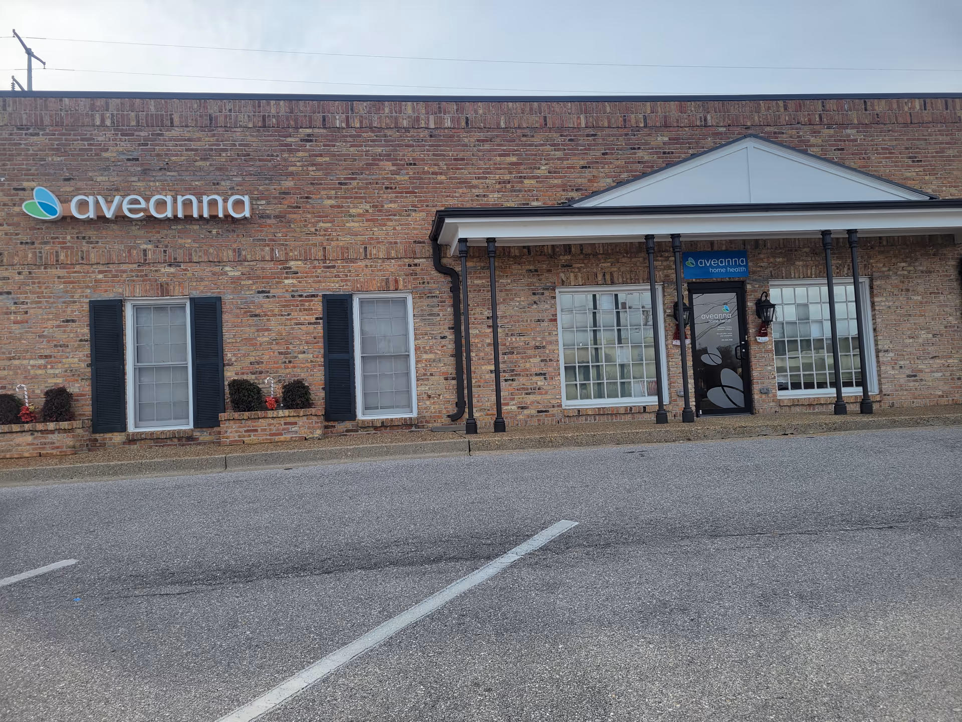 Exterior of a brick Aveanna Home Health building with entrance and signage.