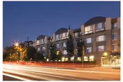 Exterior view of The Piedmont Luxury Senior Apartments at dusk with streetlights.