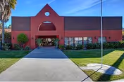 Red brick senior facility with arched entrance and green lawn.