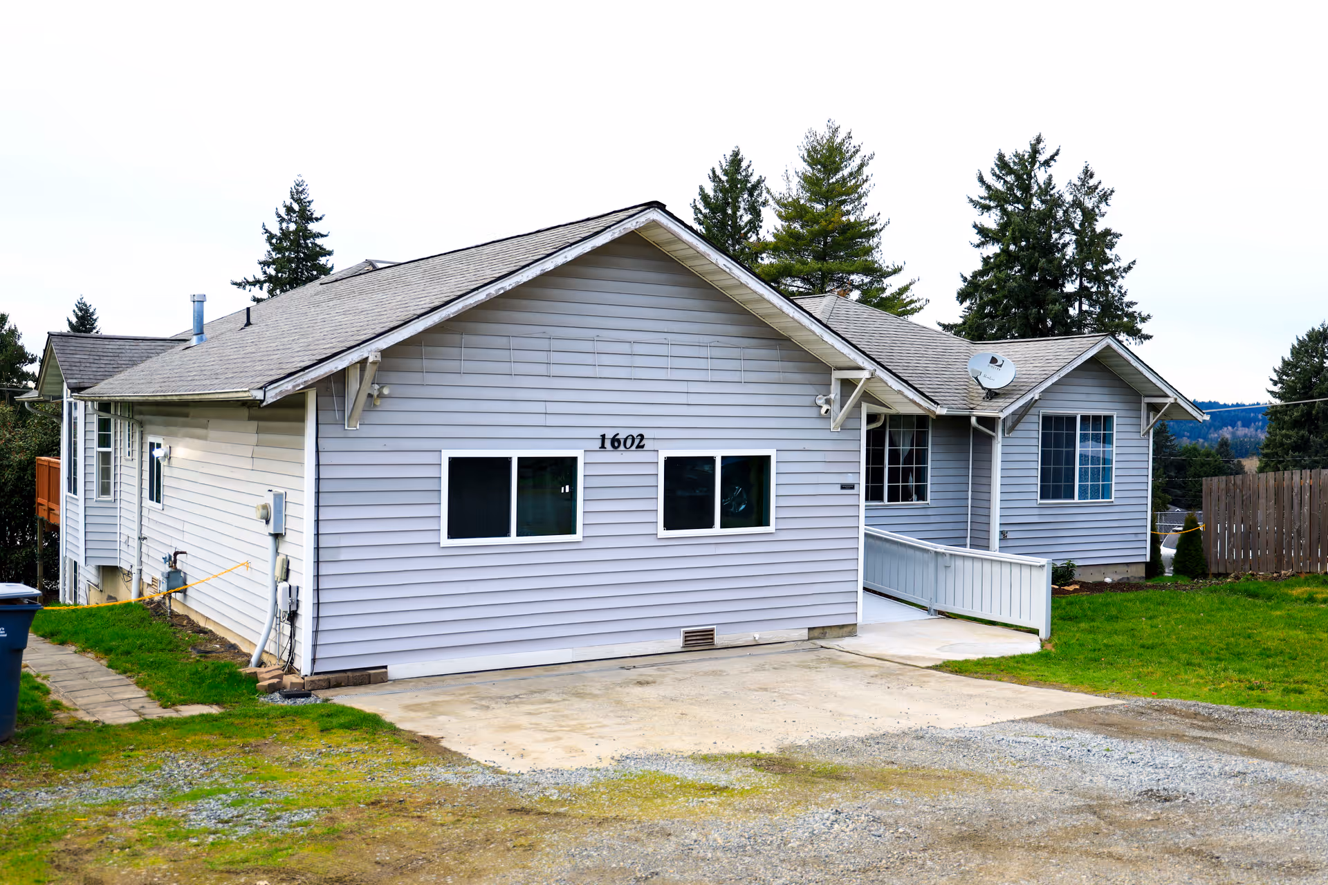 Gray single-story senior living facility with front windows and a driveway.