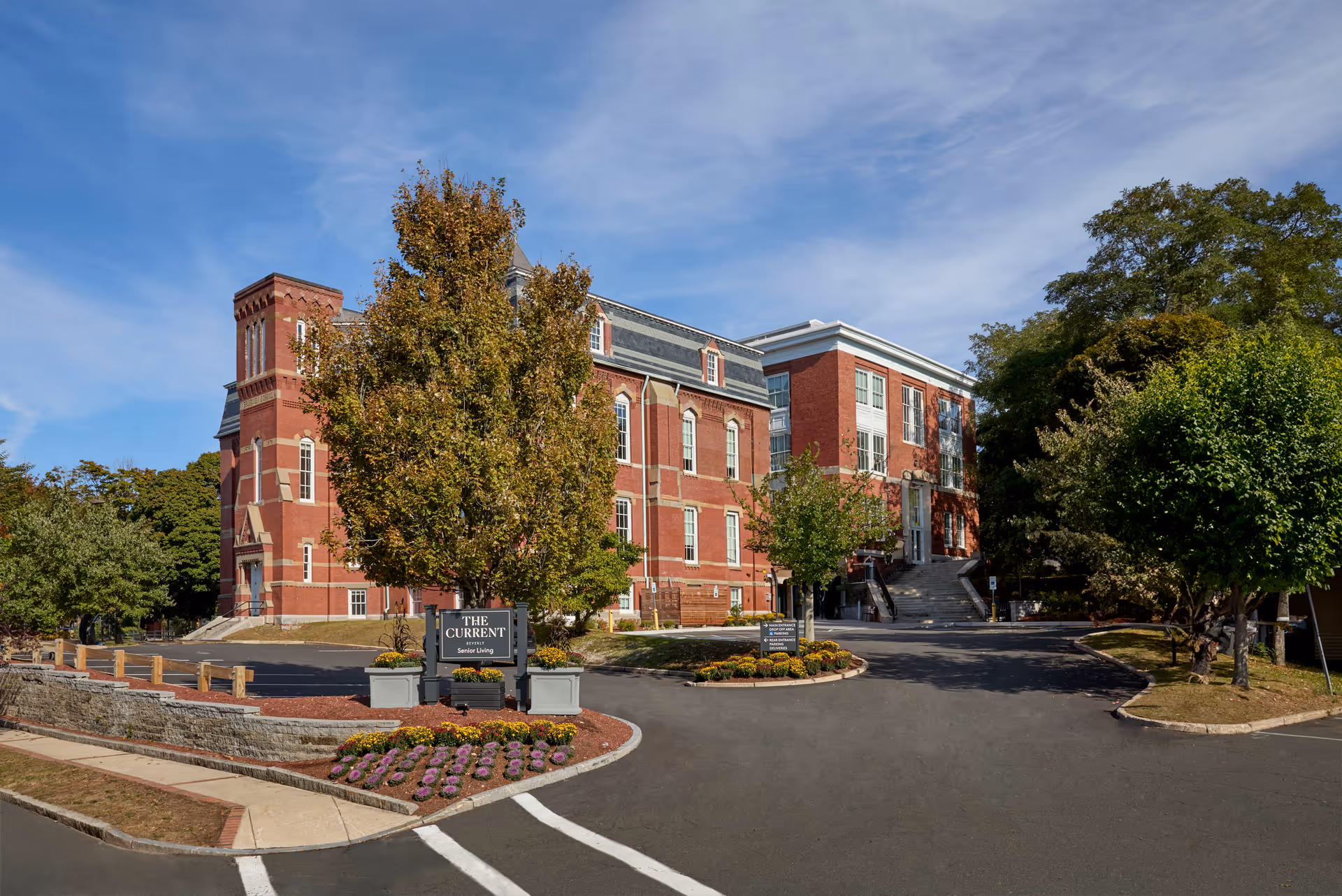 Brick senior living building exterior with landscaped entrance and signage reading The Current Beverly