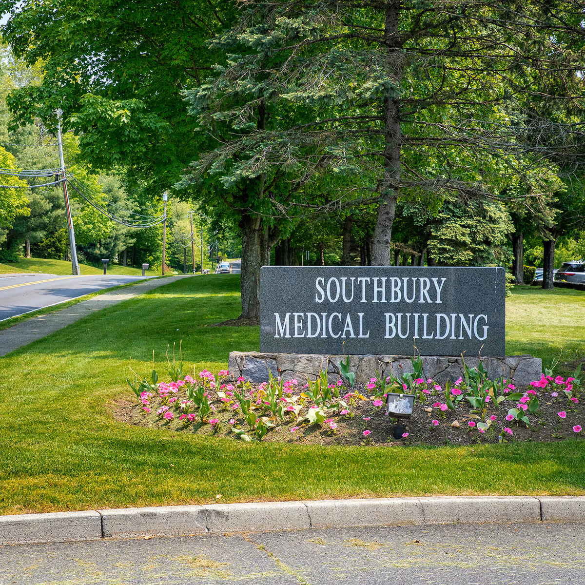 Southbury Medical Building sign surrounded by trees and blooming flowers along a road.
