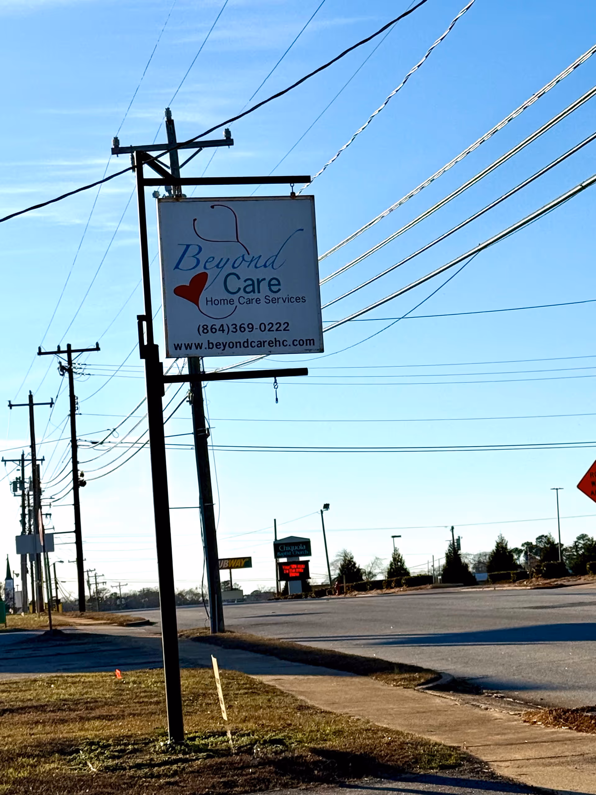 Beyond Care sign on a pole beside a road with power lines