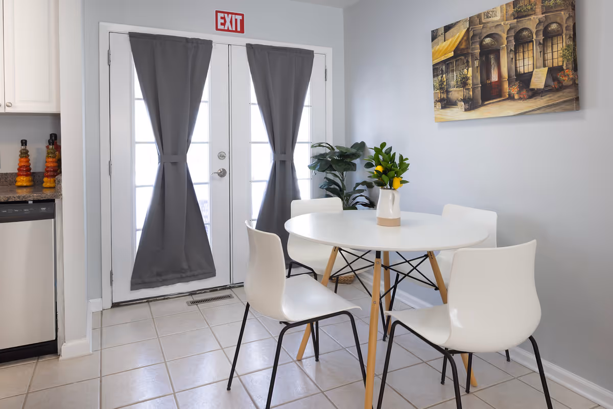 Round white dining table with four chairs in a bright, modern dining area.