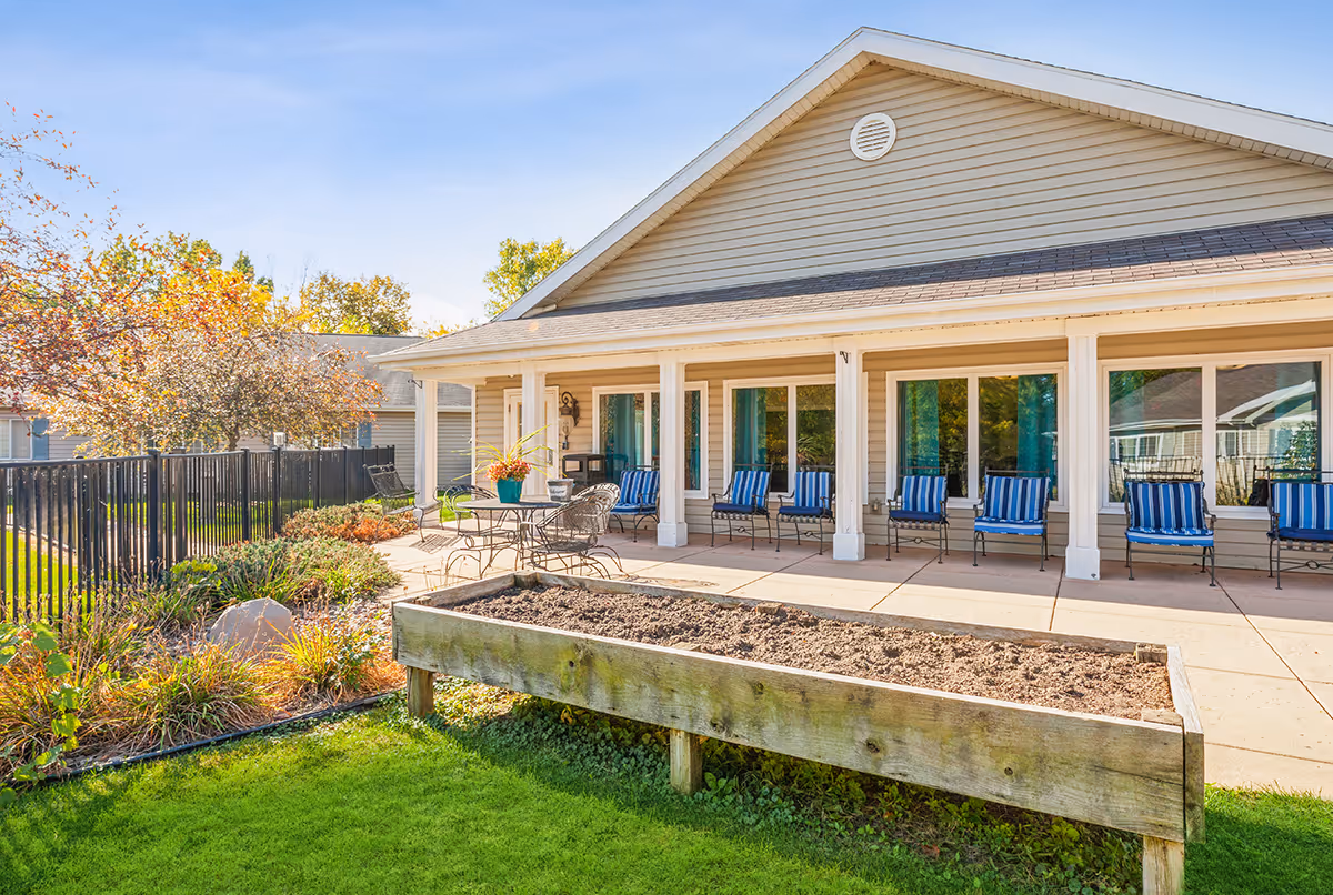 Sunny outdoor patio at Good Faith Manor with blue-striped chairs under a covered porch.