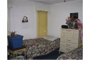 Two twin beds with floral quilts sit in a small senior facility bedroom.