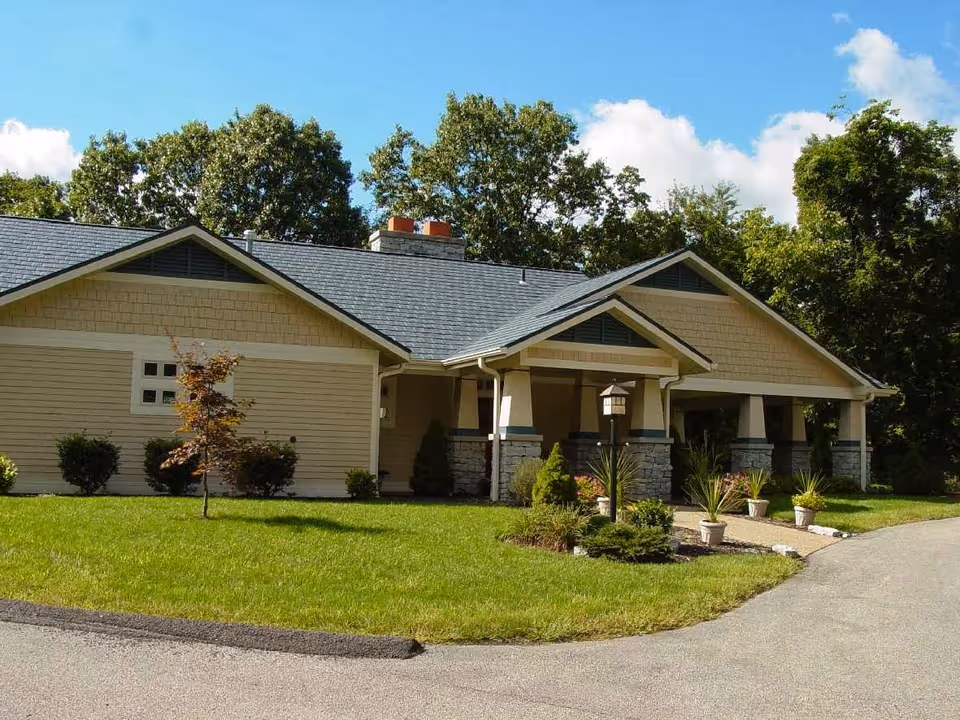 Single-story beige building with stone accents, landscaped front yard, and curved driveway.