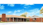 Exterior of a single-story brick senior living facility with a covered entrance.