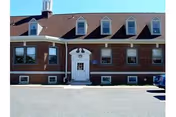 Brick building with a white entry door and dormer windows.