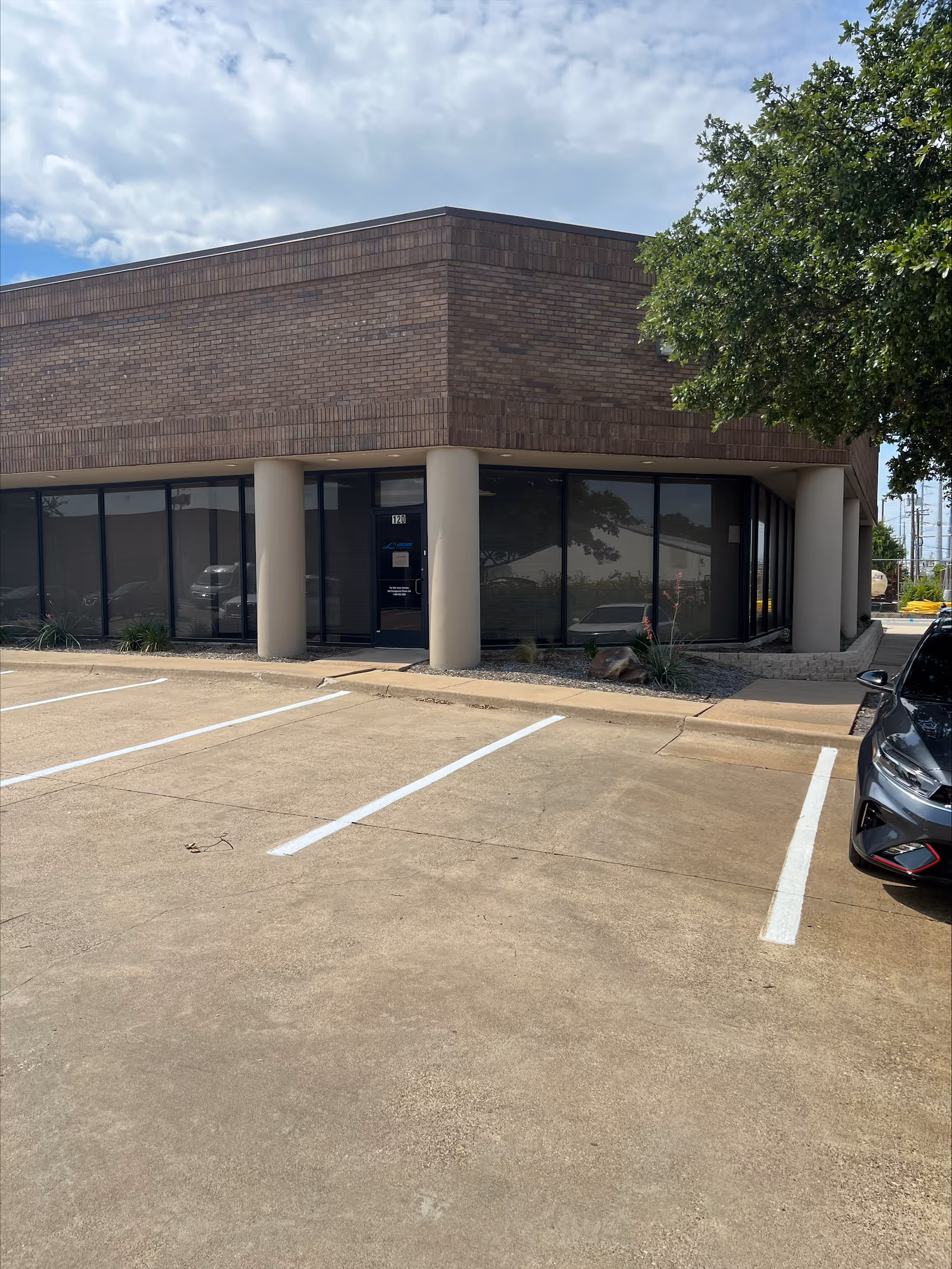 Exterior view of a brick senior living facility with entrance and parking.