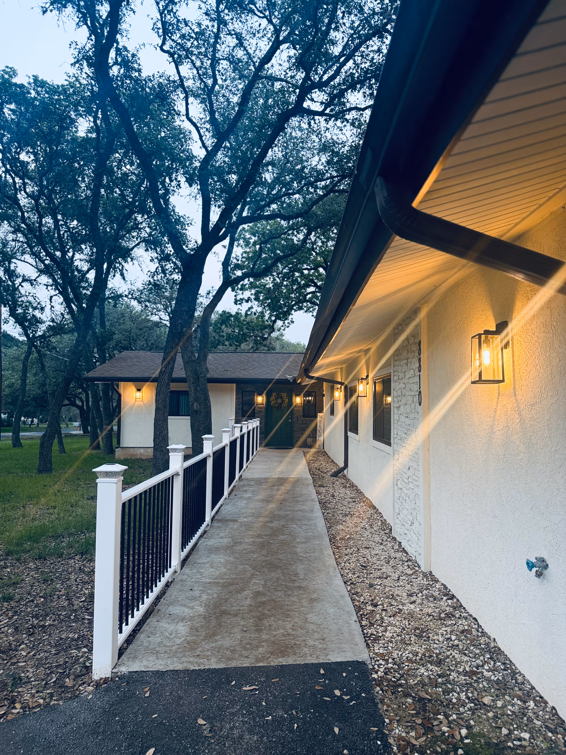 Exterior walkway along a senior living facility with railings and trees.