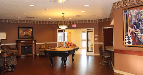 Indoor communal lounge with pool table, seating, fireplace, and artwork.
