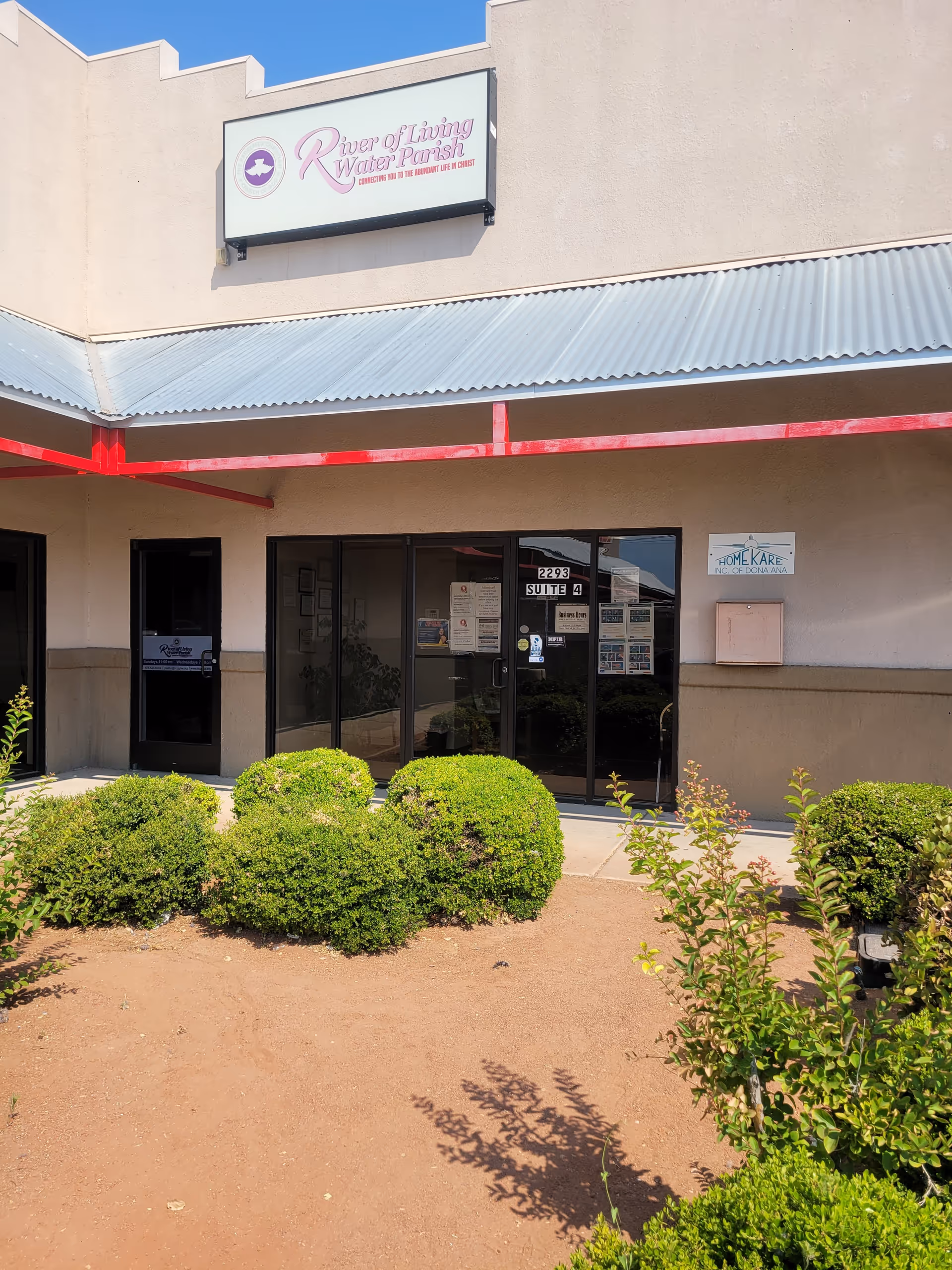 Front view of Home Kare Inc of Dona Ana facility with glass doors and shrubs.