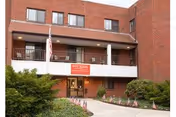 Front view of West Revere Health Center building with entrance, flag, and greenery.