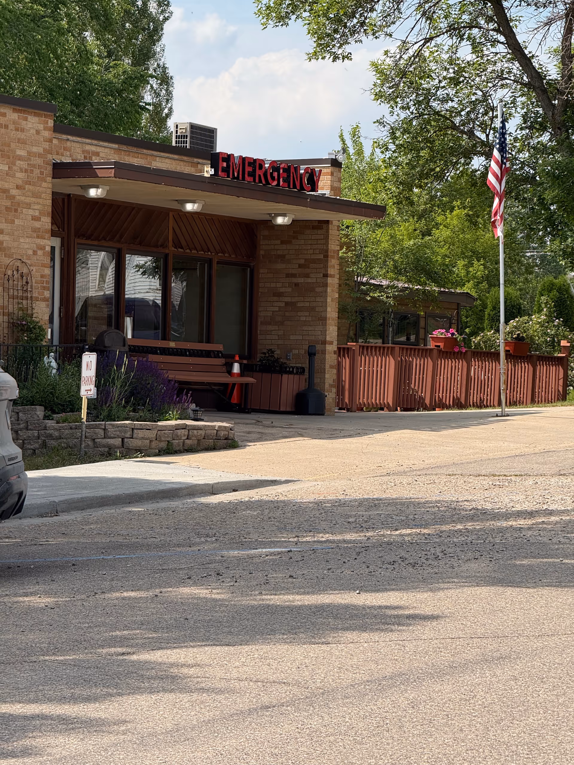 Exterior of a brick facility featuring an emergency entrance and American flag.