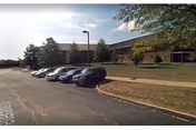 Exterior view of Thomson-Hood Veterans Center with cars parked in front and trees.