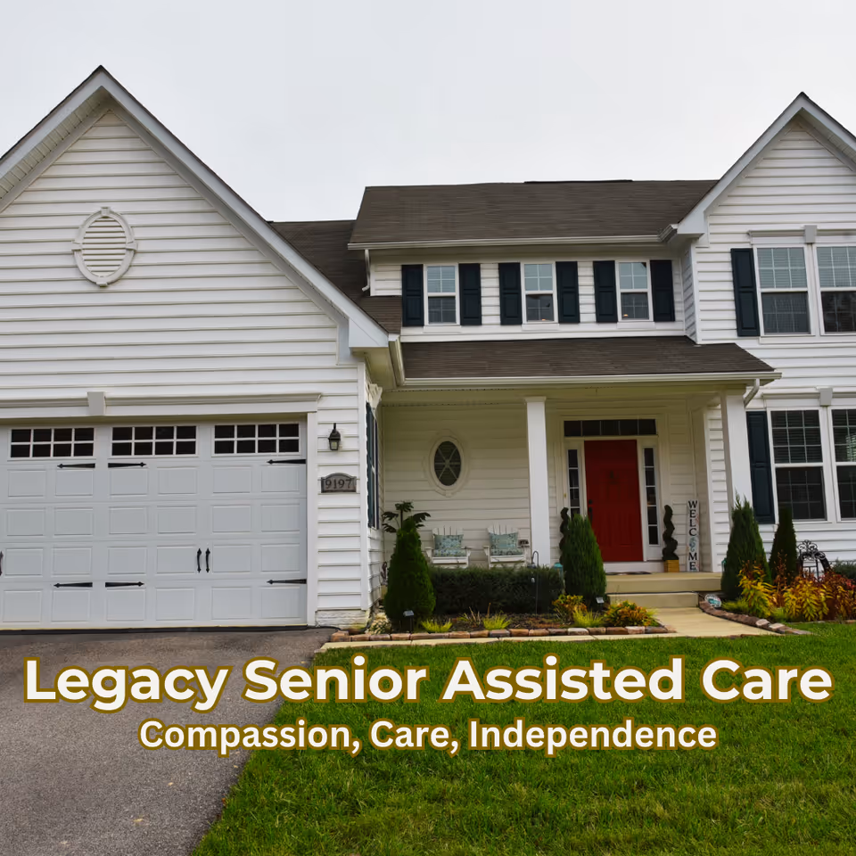 Front exterior of a white two-story senior care facility with a red door.