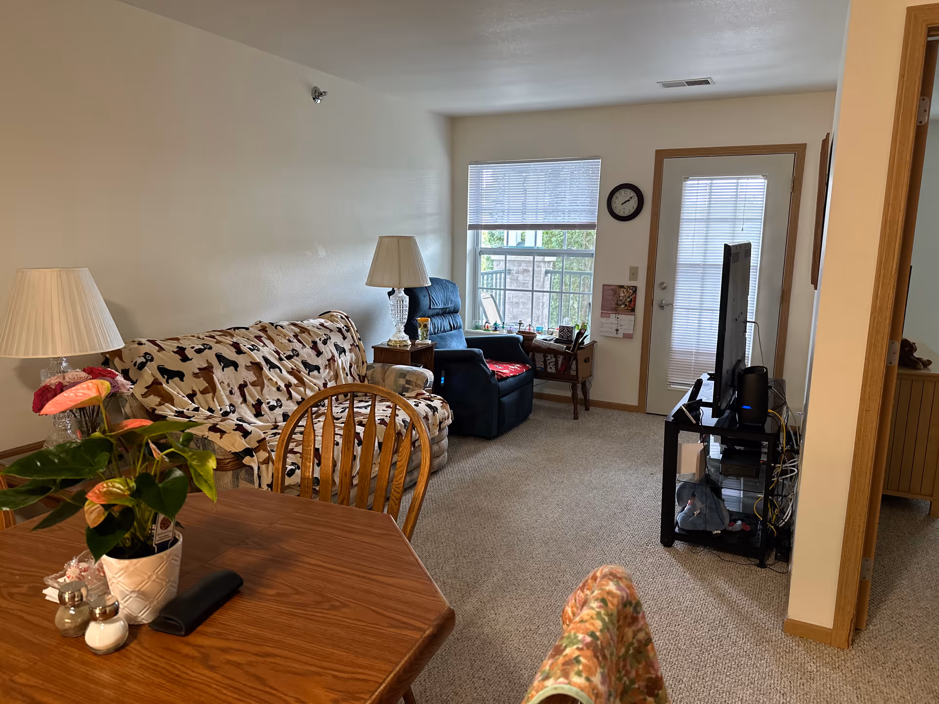 Cozy living room with sofa, recliner, TV stand, and dining table.