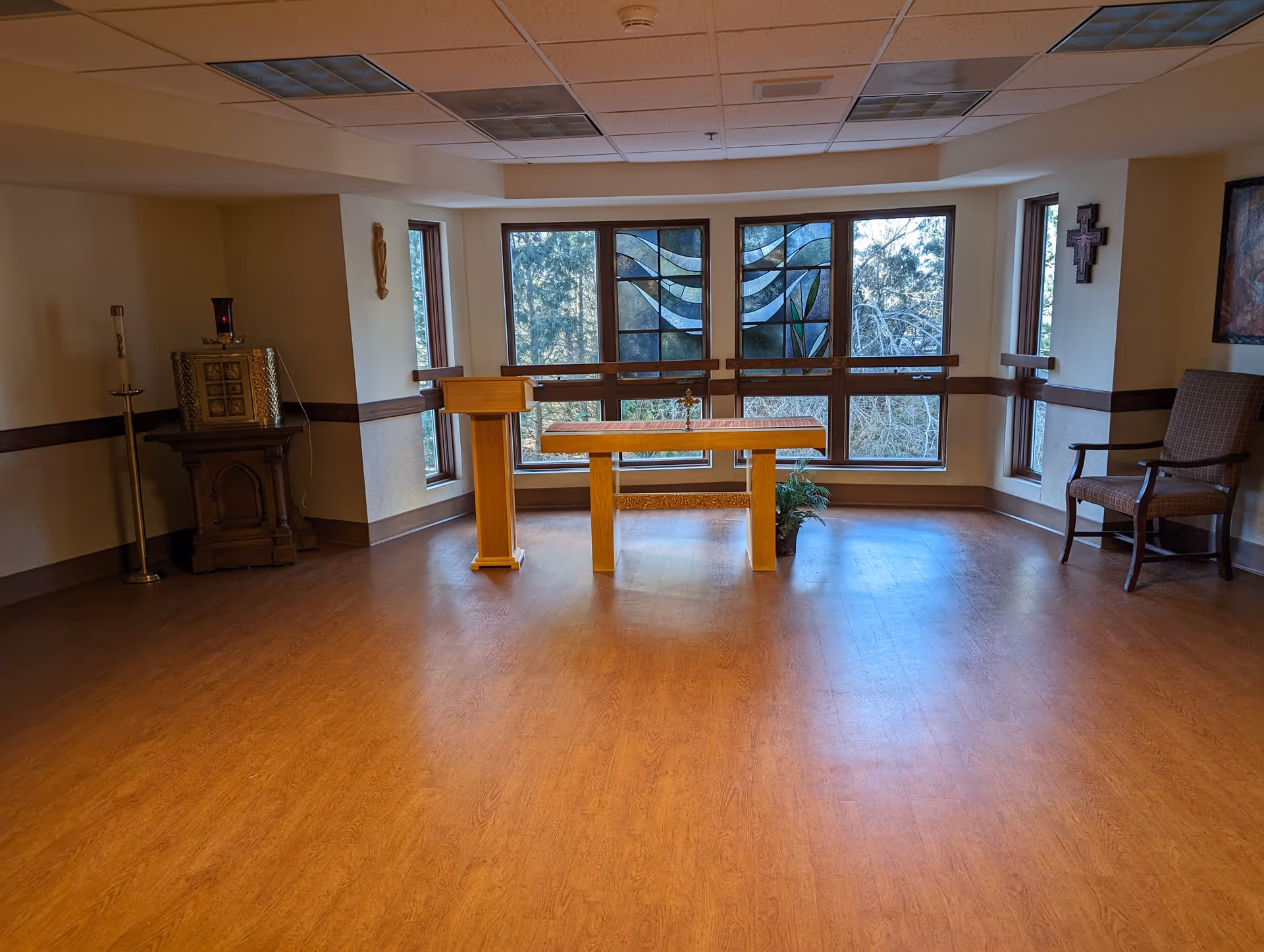 Interior chapel at Ascension Living Franciscan Place with altar, lectern, cross, and stained glass window.