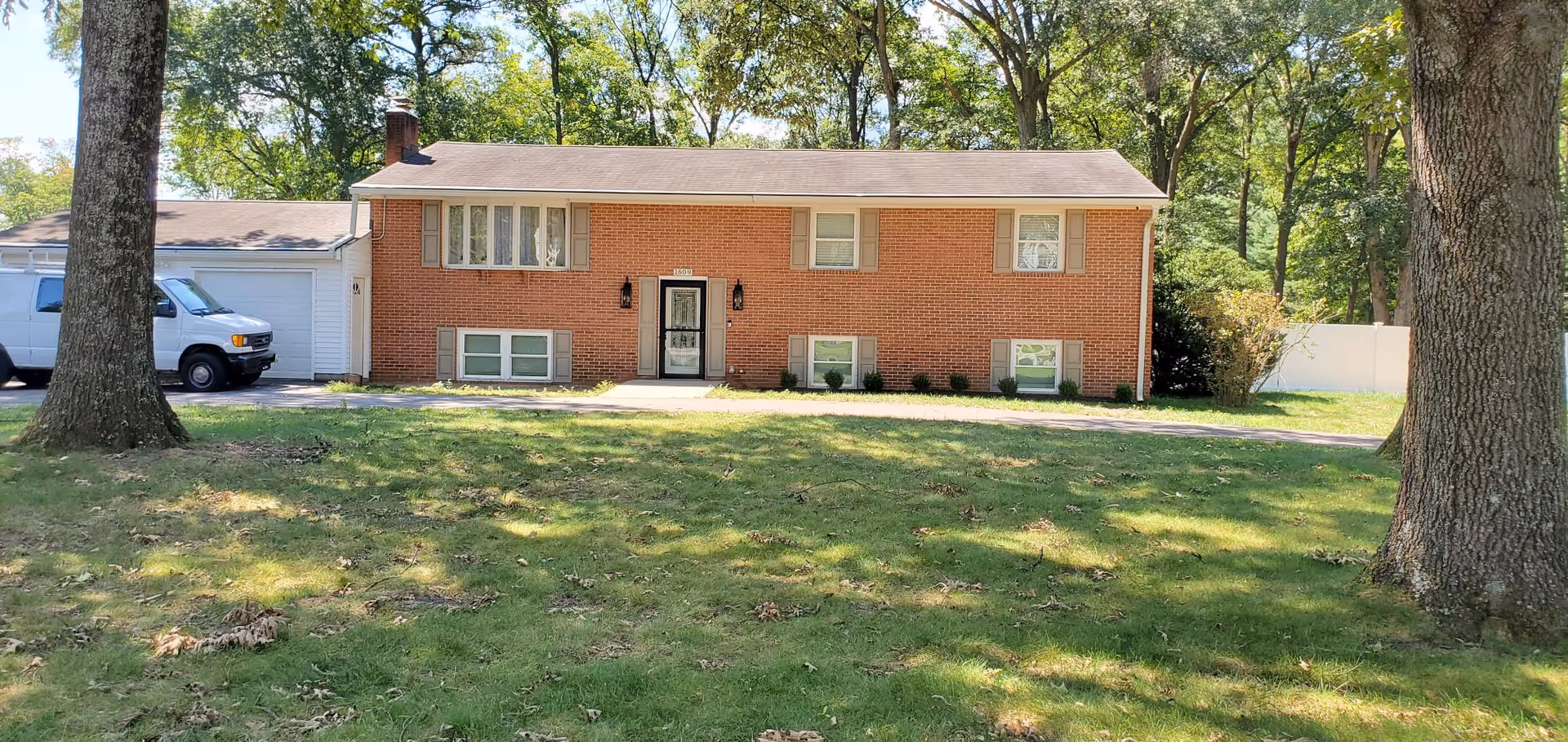 Brick ranch-style building with a front door, windows, driveway, and grassy lawn.