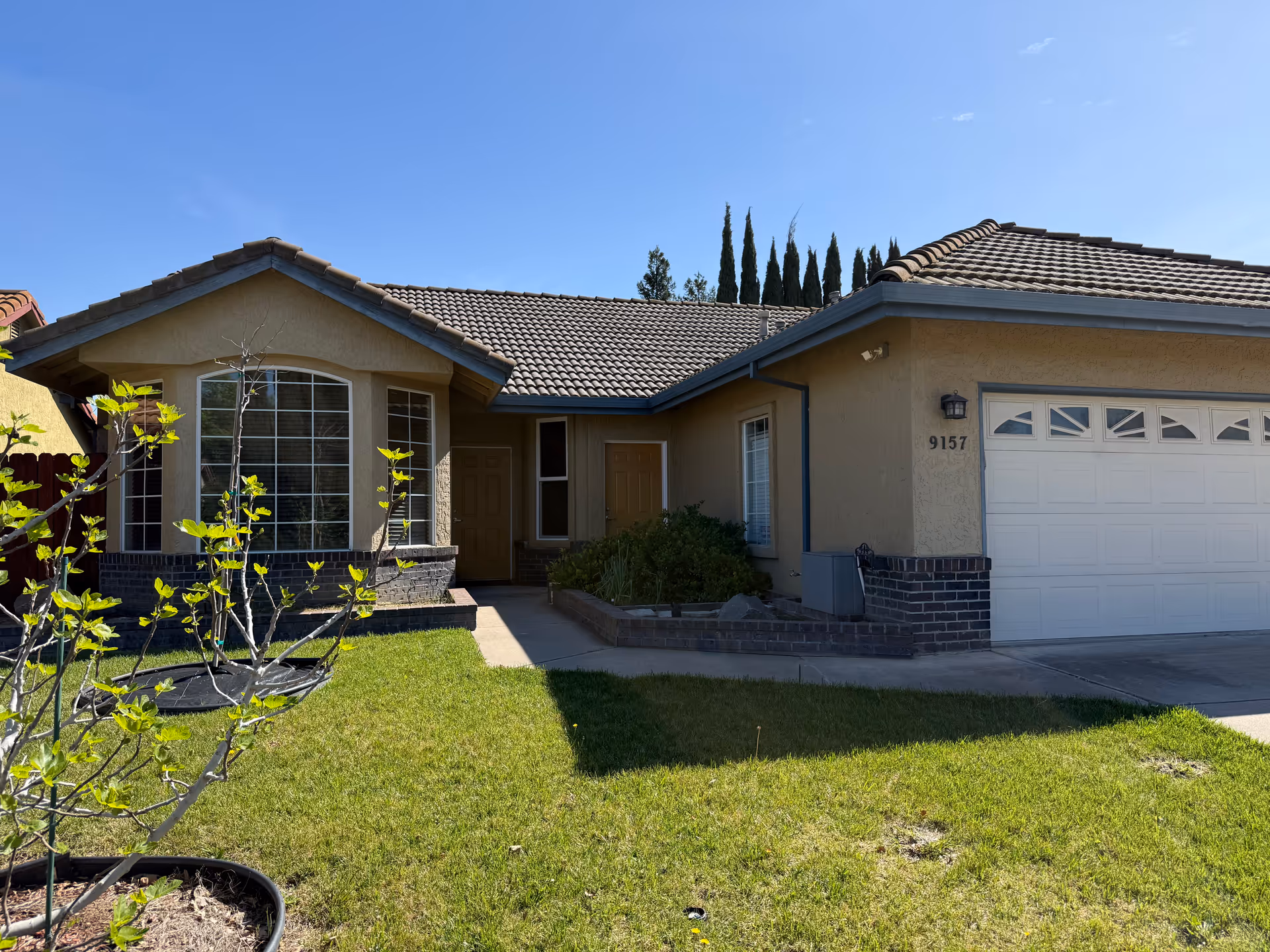 Front exterior of a single-story house with a two-car garage and green lawn.